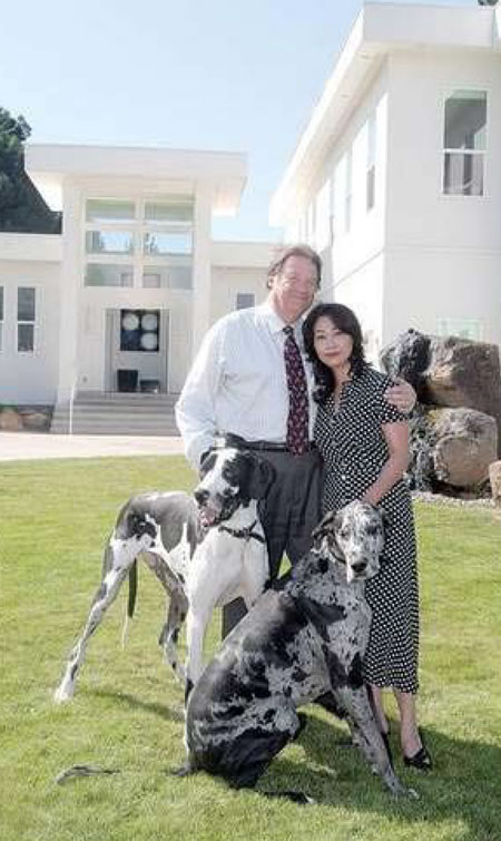 Stan and Rika Turel stand with their dogs, Andy and Mick, in front of their stunning, white contemporary home.